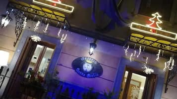 Entrada de un hotel con un letrero que dice 'Osteria Donna Giulia' e iluminación decorativa.