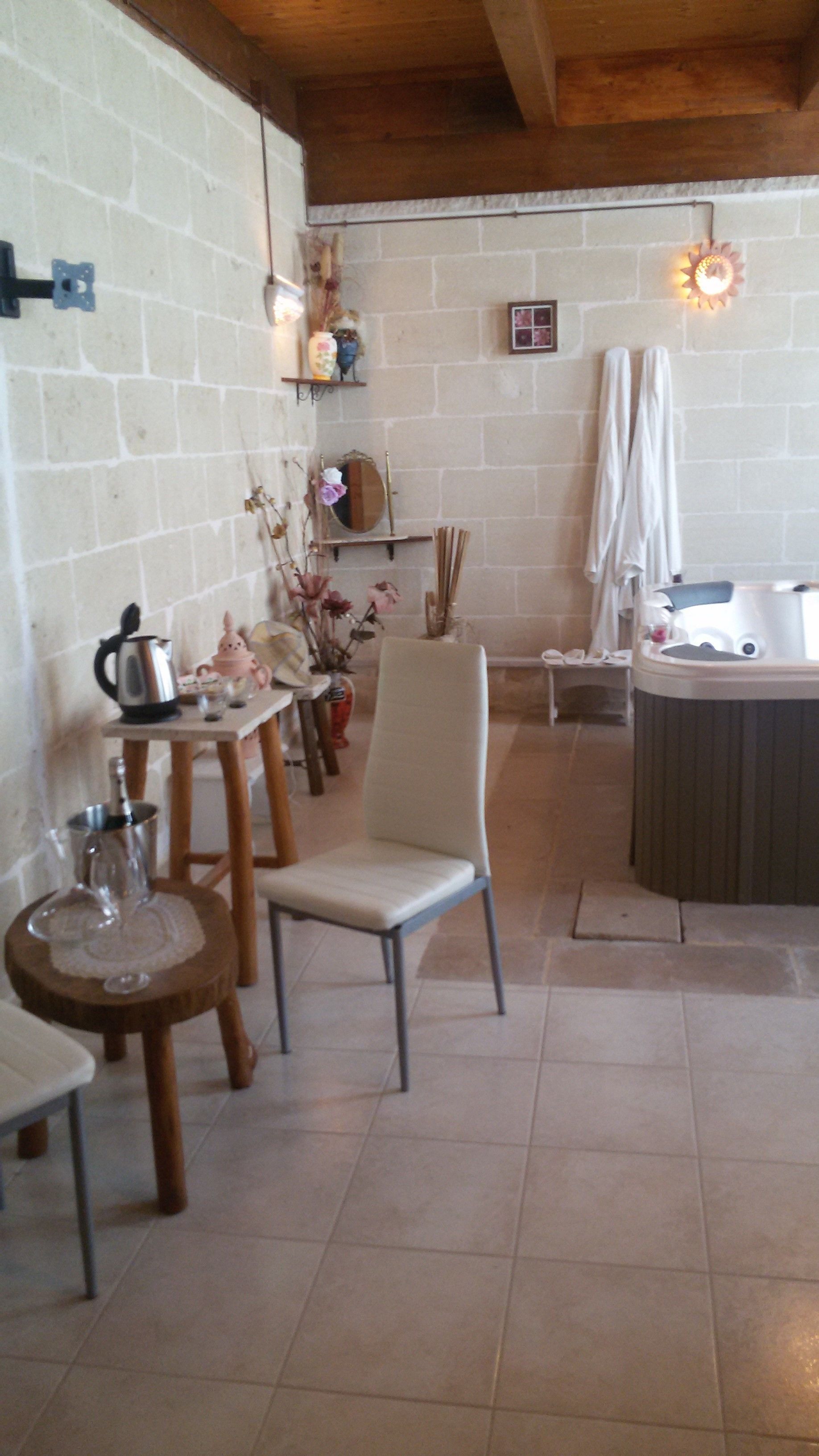 Un comedor acogedor con una mesa de madera, sillas y una pequeña zona de cocina, además de un jacuzzi.