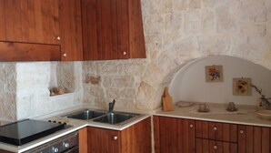 Una cocina con armarios de madera, una pared de piedra y un horno empotrado.