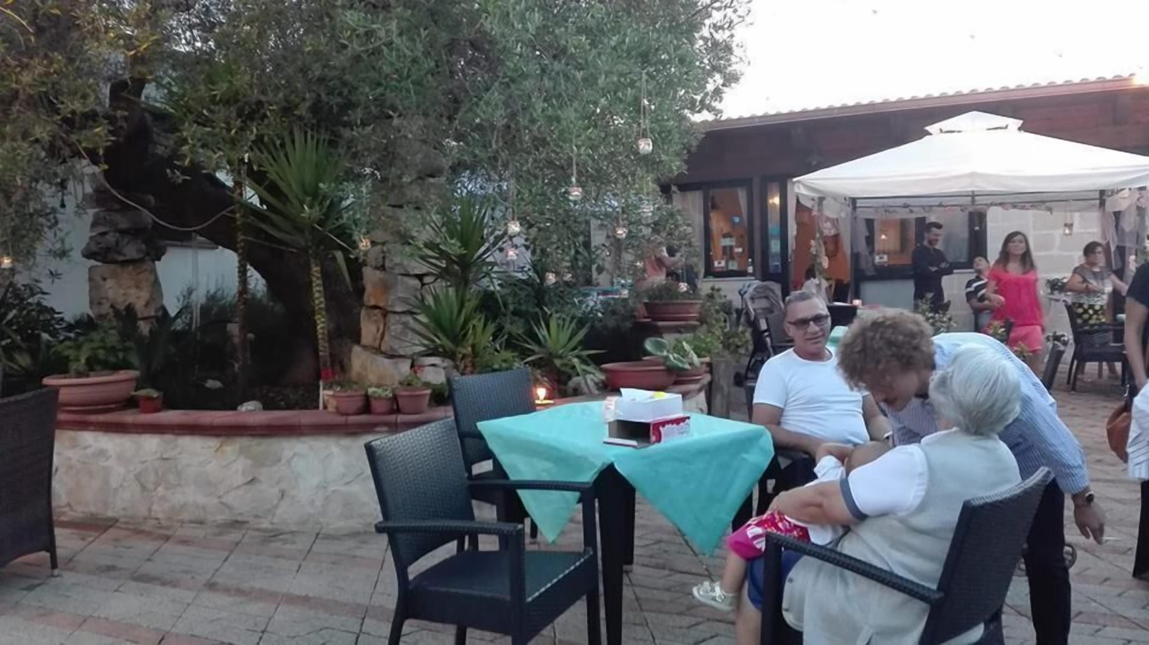 An outdoor seating area with stone walls, potted plants, and a table with a teal tablecloth.