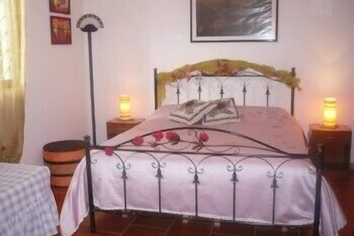 A bed with a metal frame, a headboard with a floral design, and two bedside lamps.