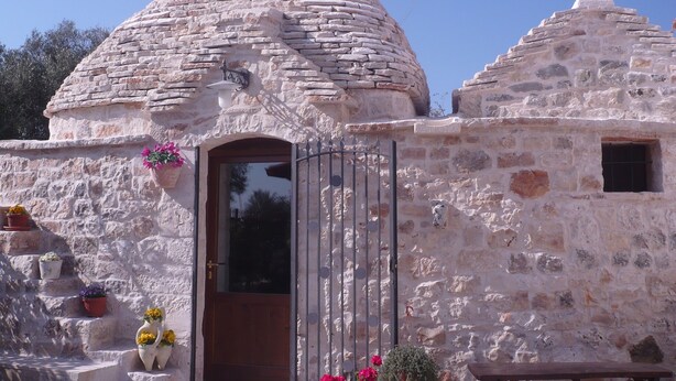 Un edificio de piedra con techo cónico, puerta de madera y una ventana pequeña.