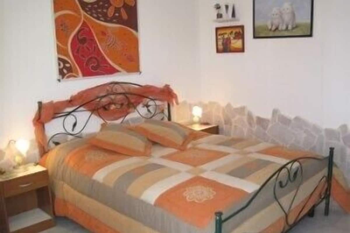 A bedroom with a bed, nightstands, and a wall with artwork.