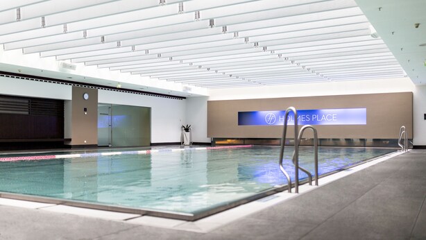 An indoor swimming pool with a modern design, a visible logo on the wall, and a clear ceiling structure. - Hotel am Augustinerplatz (Cologne)