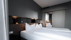 A modern hotel room with a large bed, a bedside table, a mirror, and a wall-mounted light fixture. - Hotel am Augustinerplatz (Cologne)