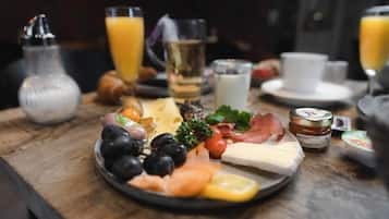 A breakfast spread with cheese, ham, olives, and tomatoes on a plate.