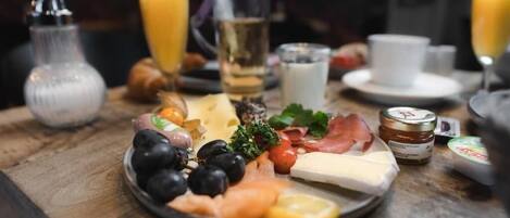 A breakfast spread with cheese, ham, olives, and tomatoes on a plate.