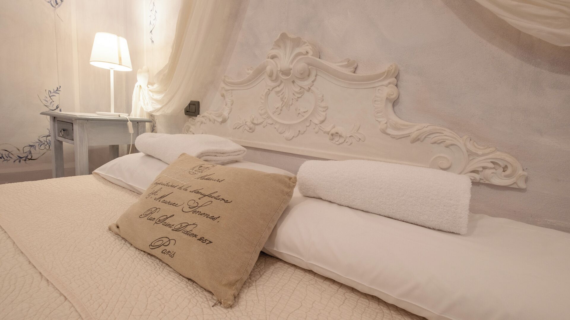A neatly made bed with white linens and a beige pillow with text.