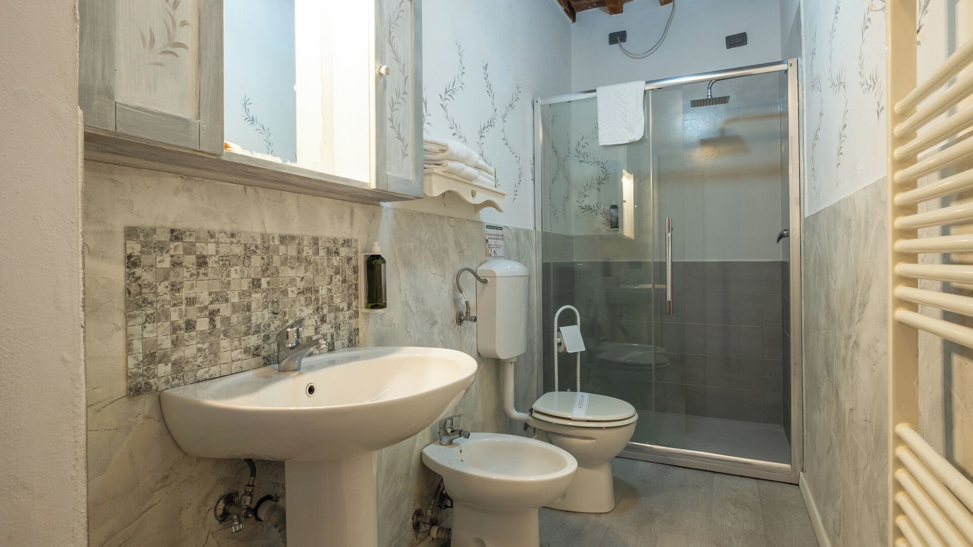 Une salle de bain équipée d’un lavabo, de toilettes, d’un bidet et d’une douche à parois en verre.