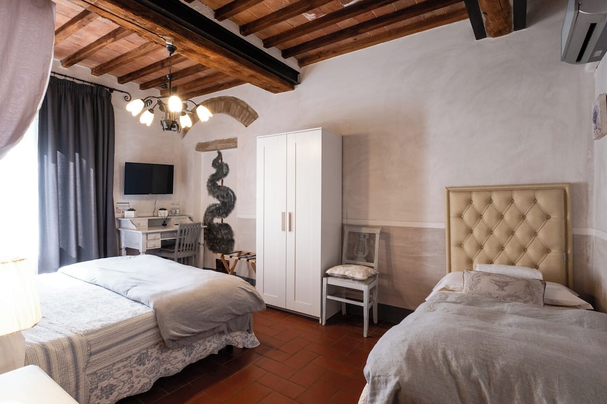 A bedroom with two beds, a desk, a wardrobe, and a television.