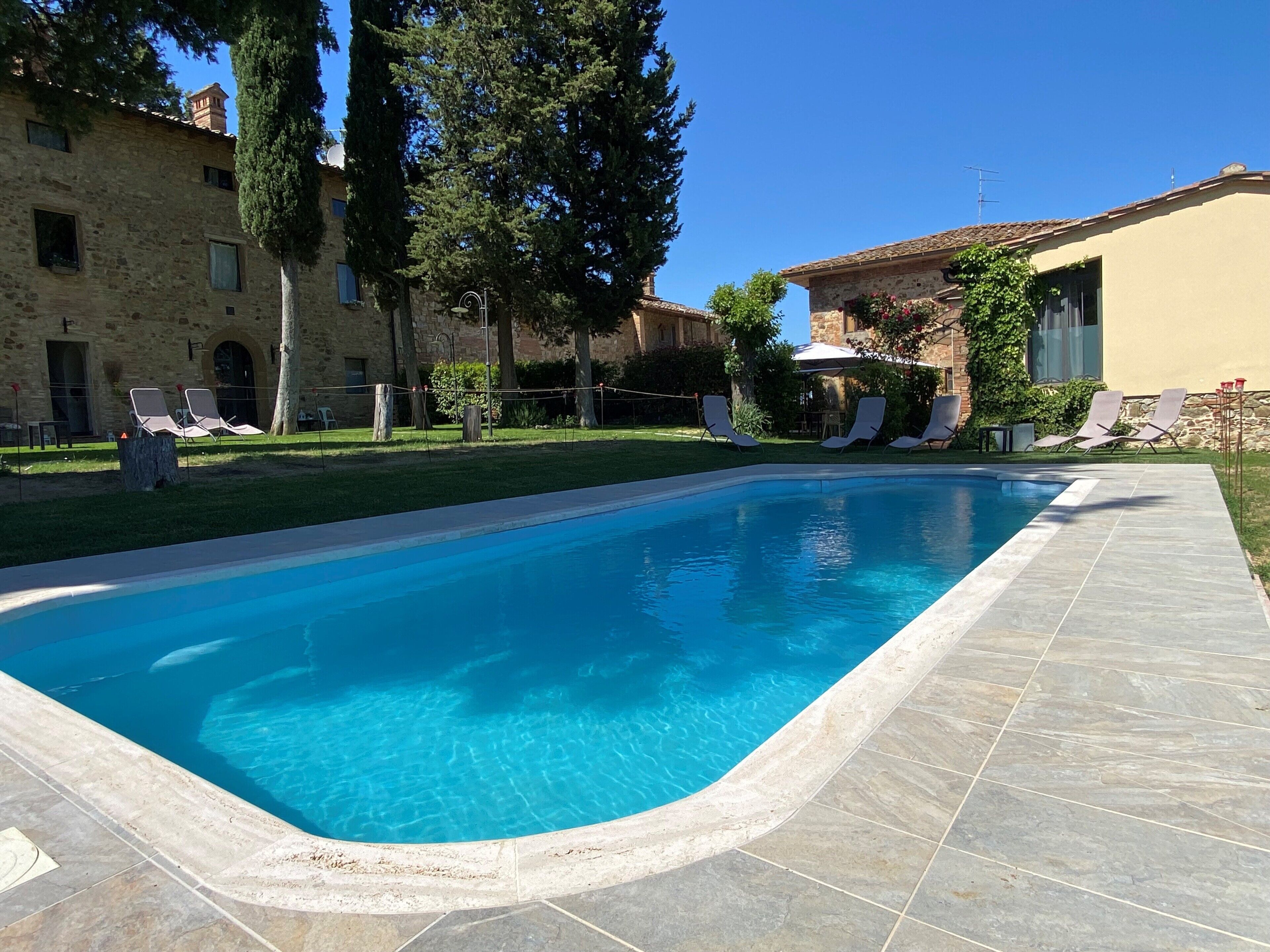 Una piscina al aire libre, sillones reclinables de piscina