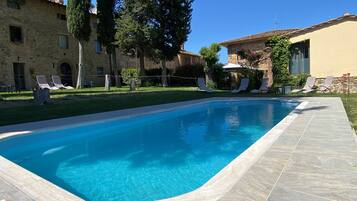 Una piscina al aire libre, sillones reclinables de piscina