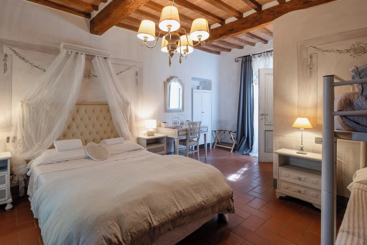 A bedroom with a large bed, a nightstand, a desk, and a chair.