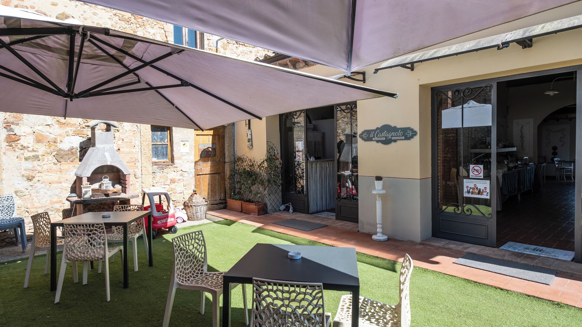 Eine Außenpatio mit Steinmauer, Pizzaofen und Tisch mit Stühlen.