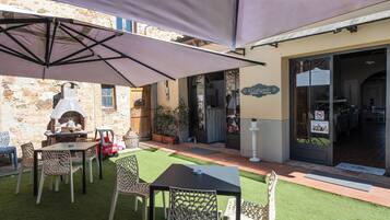 Eine Außenpatio mit Steinmauer, Pizzaofen und Tisch mit Stühlen.