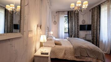 Une chambre avec un grand lit, une table de chevet avec une lampe, un miroir et un téléviseur fixé au mur.