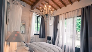 A bedroom with a bed, a lamp, a chandelier, and curtains.