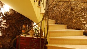 A staircase with a metal railing leading to a landing, a marble wall, and a wooden cabinet with decorative items. - Hotel Monte Baldo (Limone sul Garda)