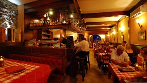 A restaurant interior with a bar area, wooden furniture, and a checkered tablecloth. - Hotel Monte Baldo (Limone sul Garda)