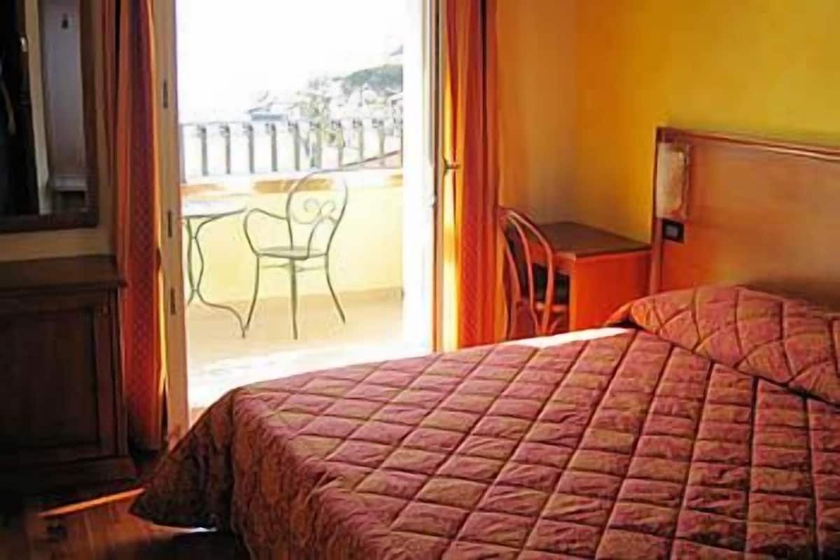 A bedroom with a bed, a desk, and a chair.