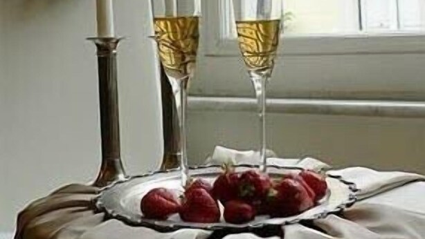 A table with two glasses of white wine, a plate of strawberries, and a candle. - Bed and Breakfast Rosmini (Rome)