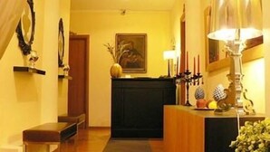 A hallway with a wooden bench, a dark-colored fireplace, and a framed painting on the wall. - Bed and Breakfast Rosmini (Rome)