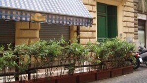 A stone building with a closed shutter, a blue awning, and a green door. - Bed and Breakfast Rosmini (Rome)