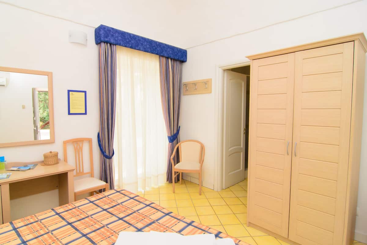 Quarto com cama, escrivaninha, cadeira, guarda-roupa e janela com cortinas.