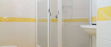 A bathroom with a shower enclosure, a toilet, and a sink.