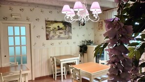 A dining area with a wooden table and chairs, a chandelier, and a wall-mounted picture. - Bed & Breakfast De Nittis - Meridia Collection (Barletta)