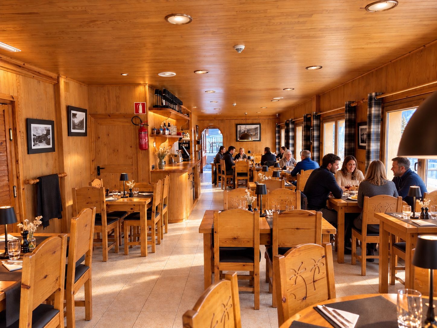 Un restaurant à l’intérieur en bois, avec de nombreuses tables et des clients assis.