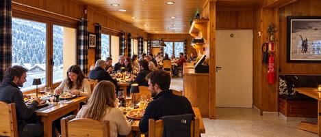 A restaurant with wooden interior, multiple dining tables, and patrons.