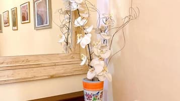 Uma cadeira de madeira com almofada branca e um vaso com orquídeas brancas sobre uma mesa de madeira.