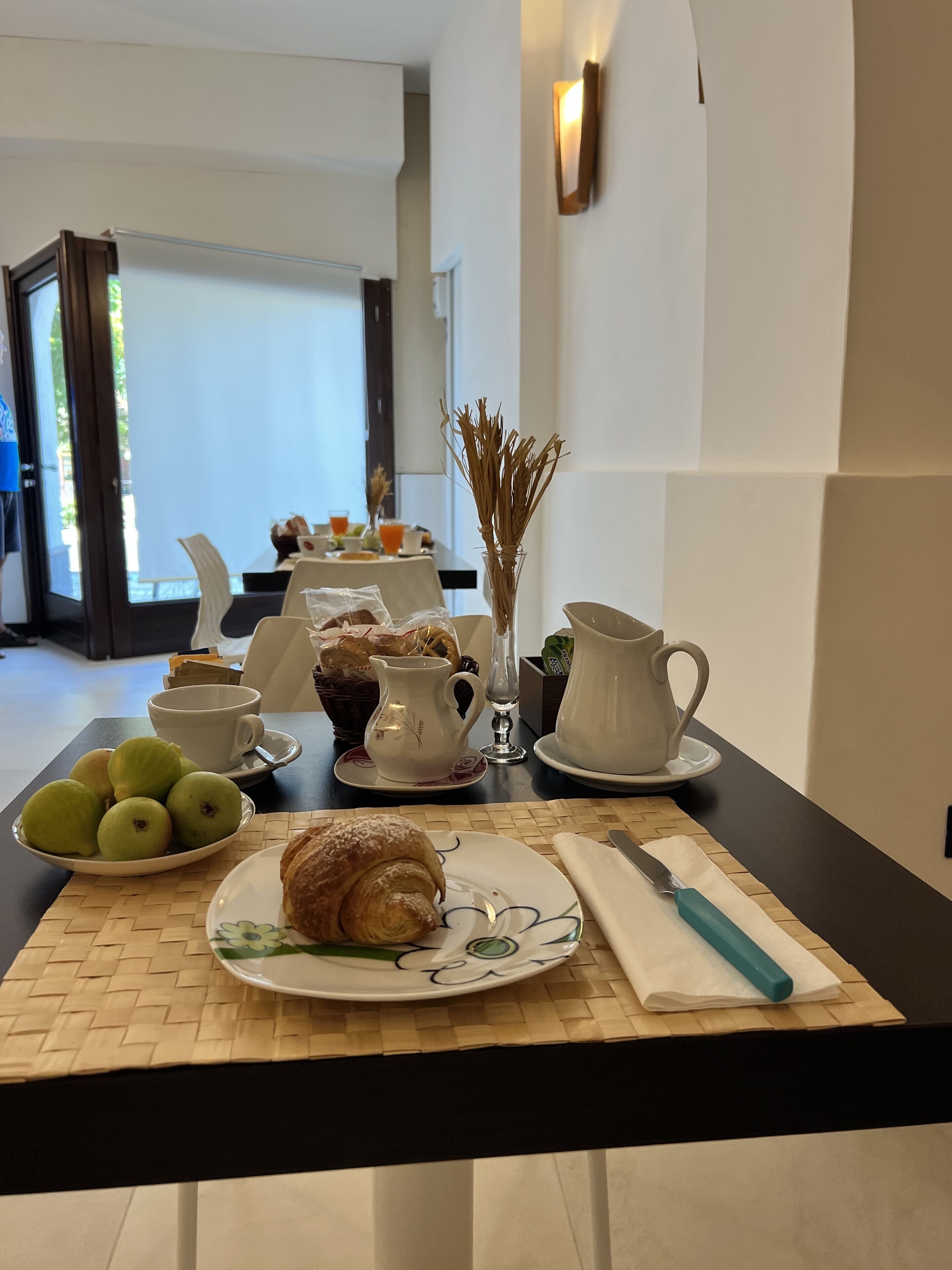 Uma mesa com um croissant, maçãs e uma xícara de café para o café da manhã.