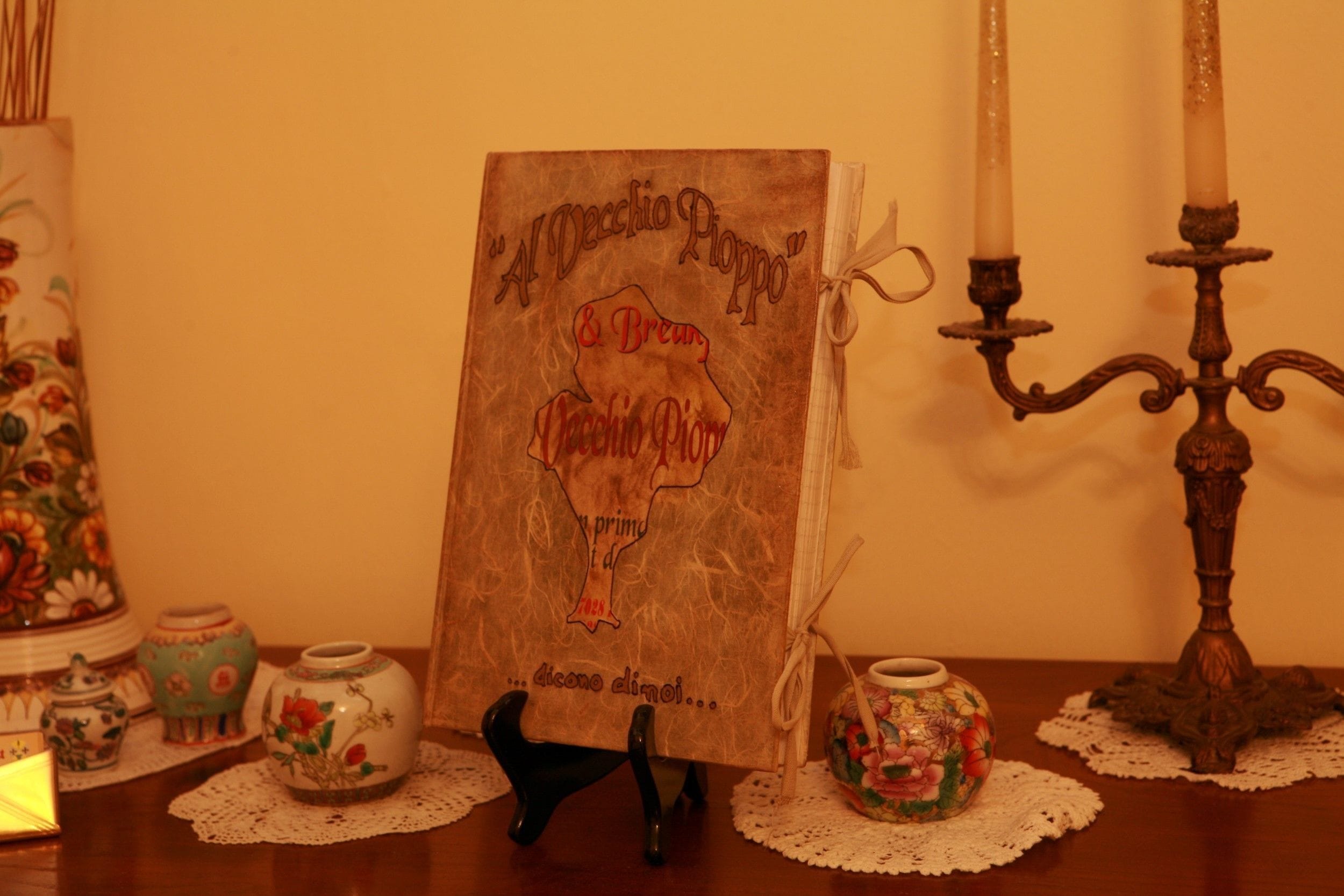 A book titled "Al Decchio Poppo" on a table with decorative items.