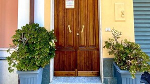 A building entrance with a wooden double door, two potted plants on either side, and a sign above the door reading "Bed & Breakfast Al Vecchio Pioppo". - Al Vecchio Pioppo (Praia a Mare)