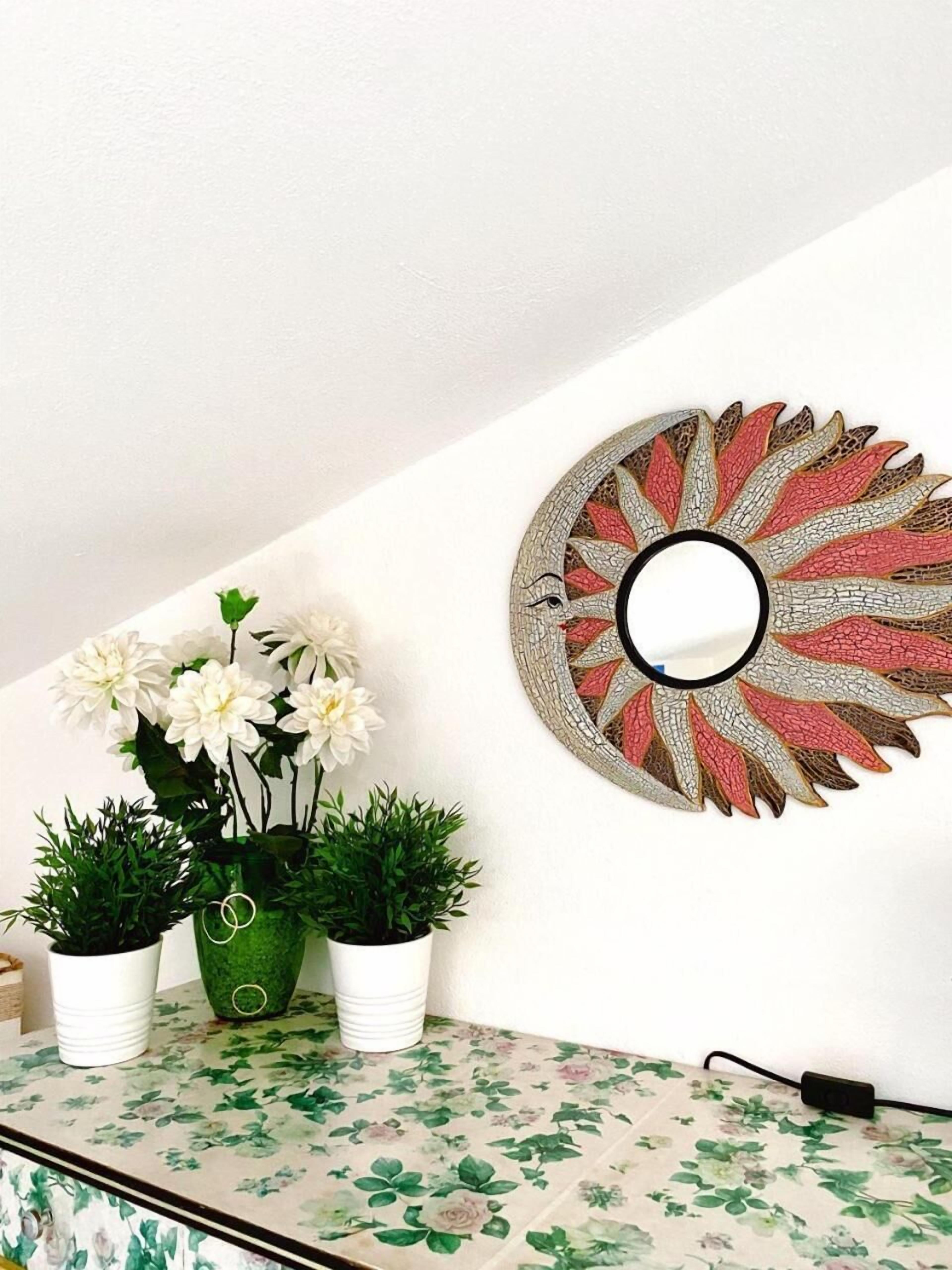 A wall with a decorative metal piece and a floral-patterned cabinet.