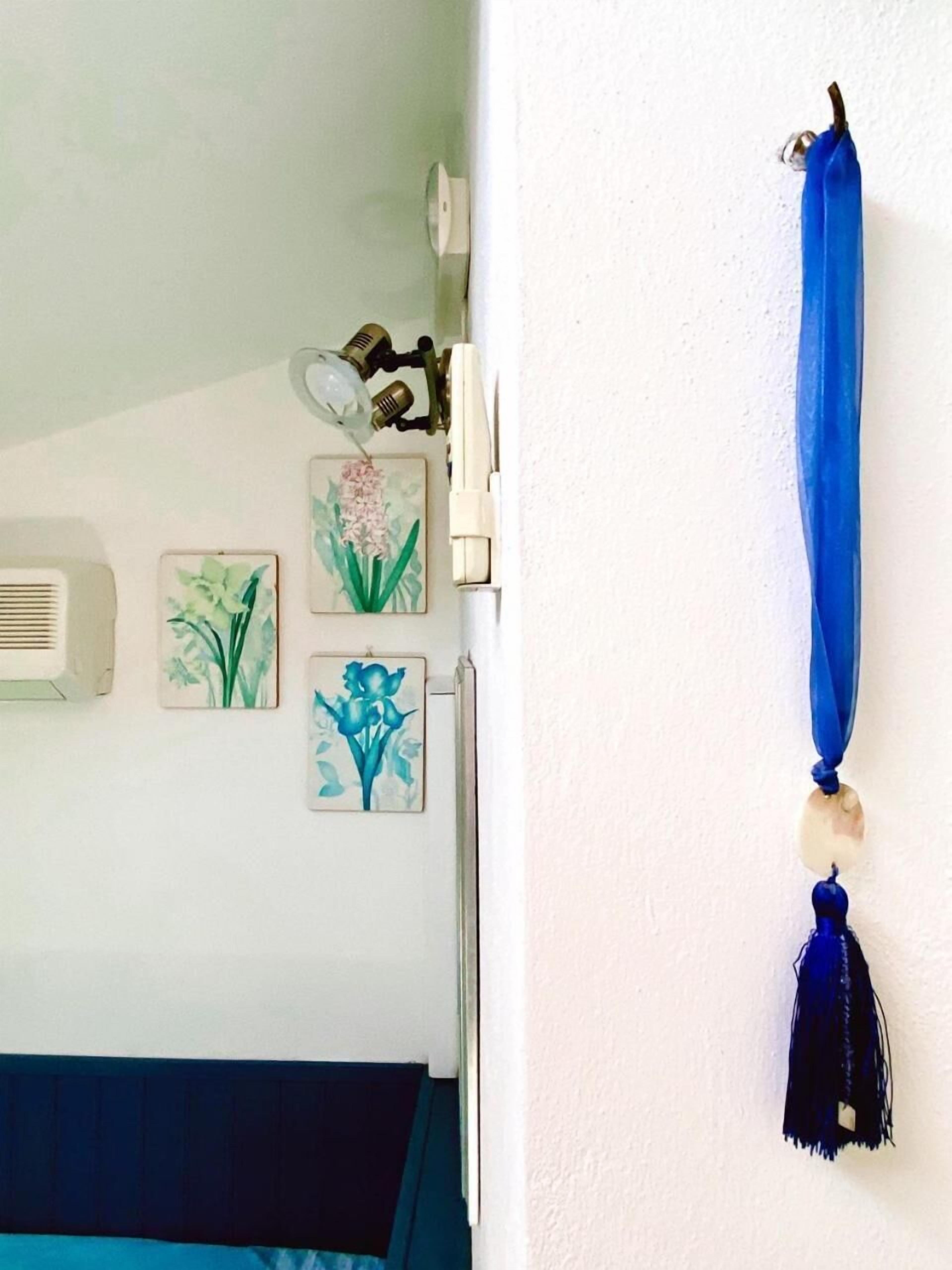 A bedroom with a bed, a wall-mounted air conditioner, and three framed floral artworks.