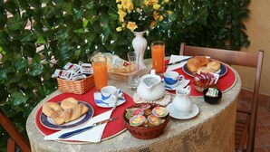 A breakfast table set with croissants, pastries, juice, and a vase of flowers. - Al Vecchio Pioppo (Praia a Mare)