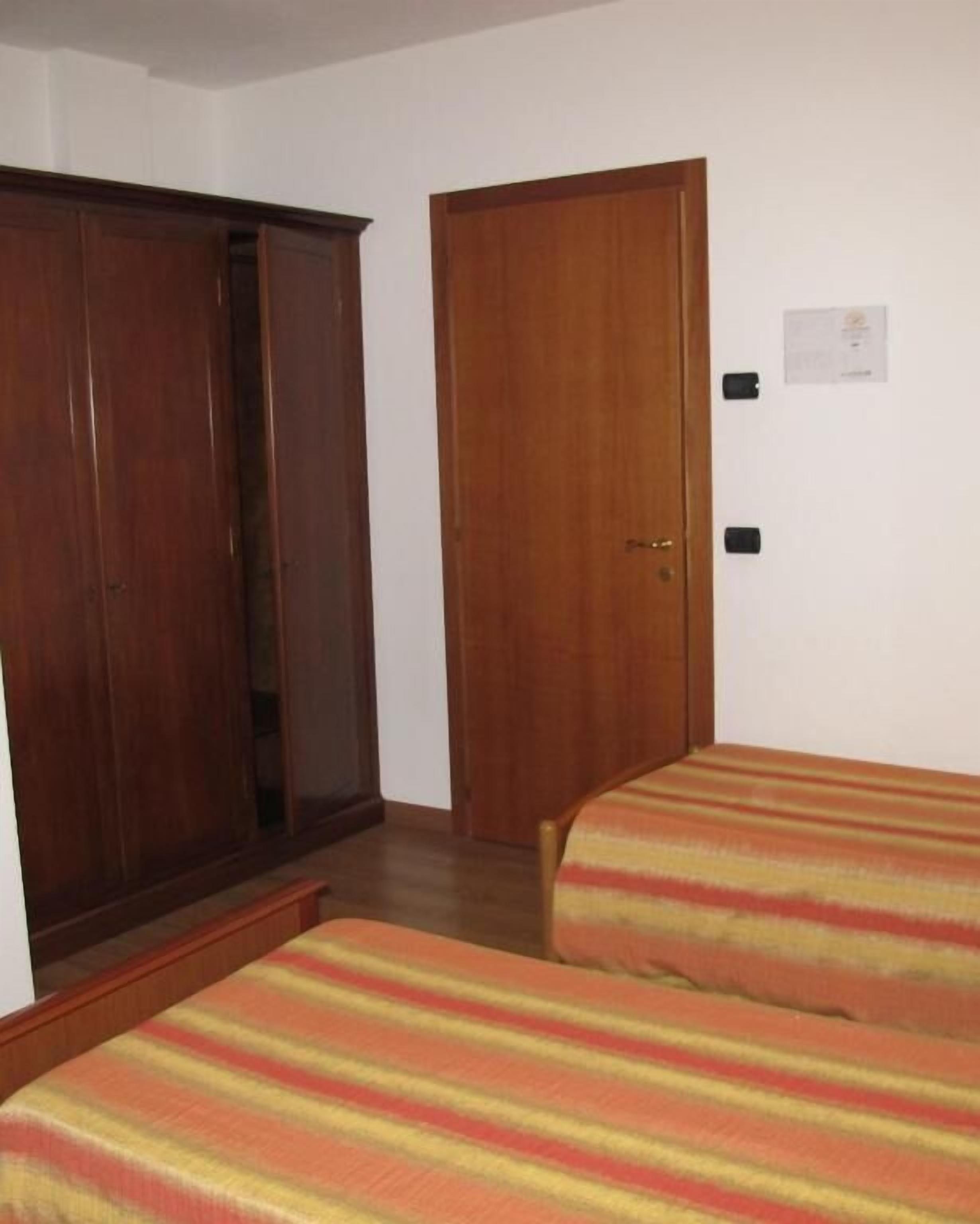 A room with two beds, wooden wardrobes, and a door.