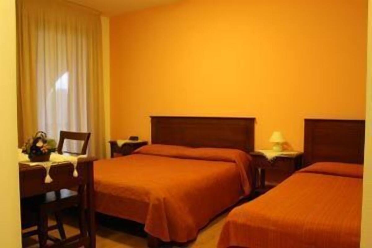 A hotel room with two beds, a desk, and a chair.