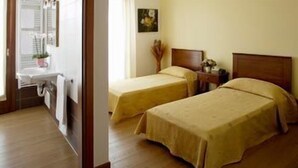 A room with two single beds, a wooden floor, a desk with a chair, and a window with blinds. - Ca' Florian (Zero Branco)