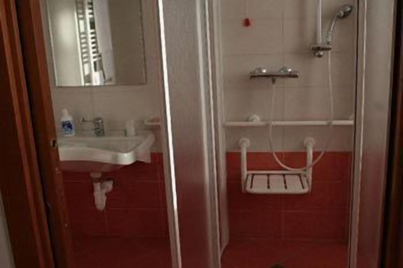 A bathroom with a white sink, a mirror, and a shower area.