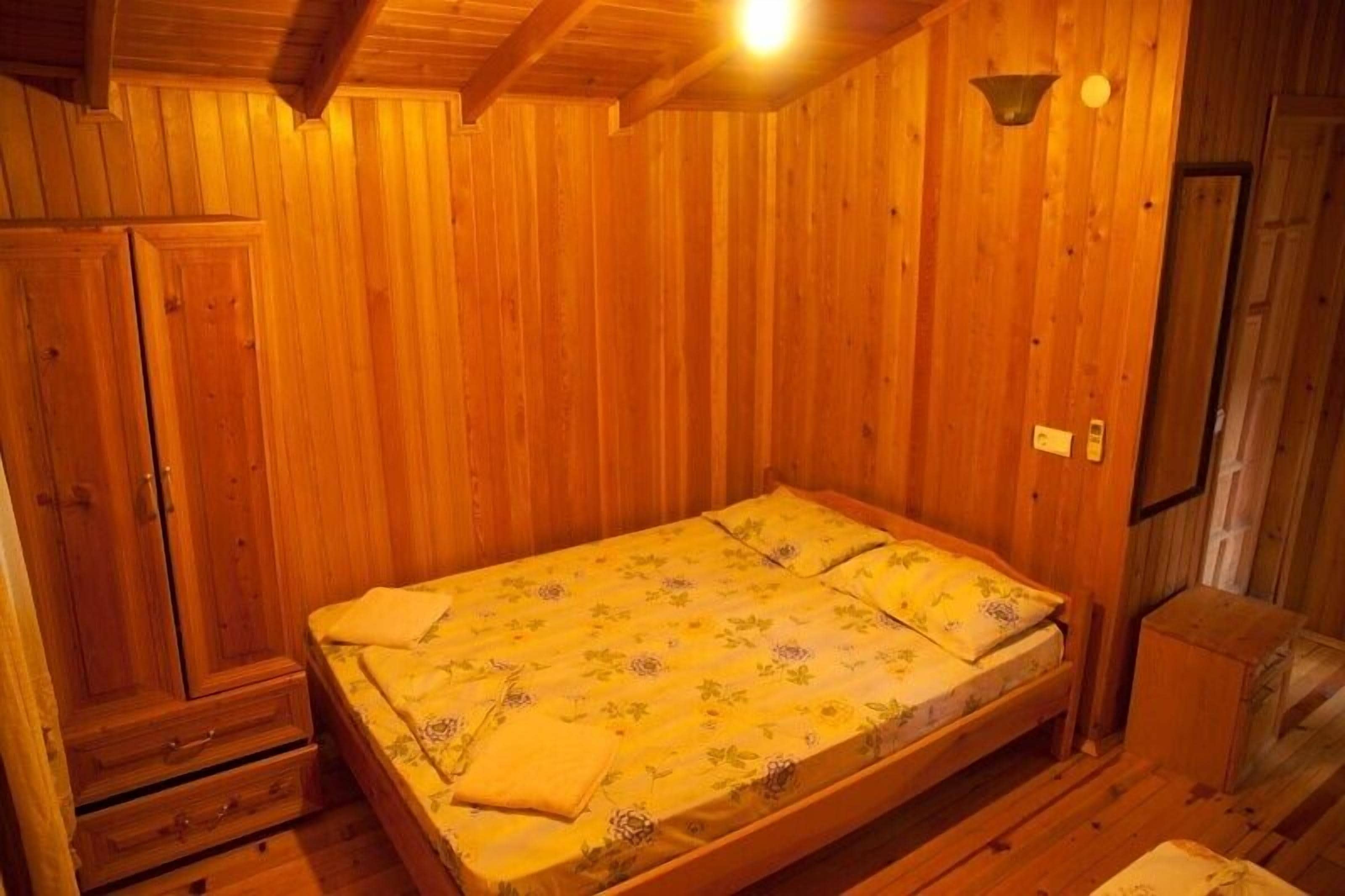 A wooden room with a bed, a wardrobe, and a small table.