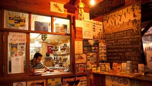 A small, wooden-fronted shop with various signs and posters advertising local attractions and services. - Bayrams Tree Houses (Kumluca)