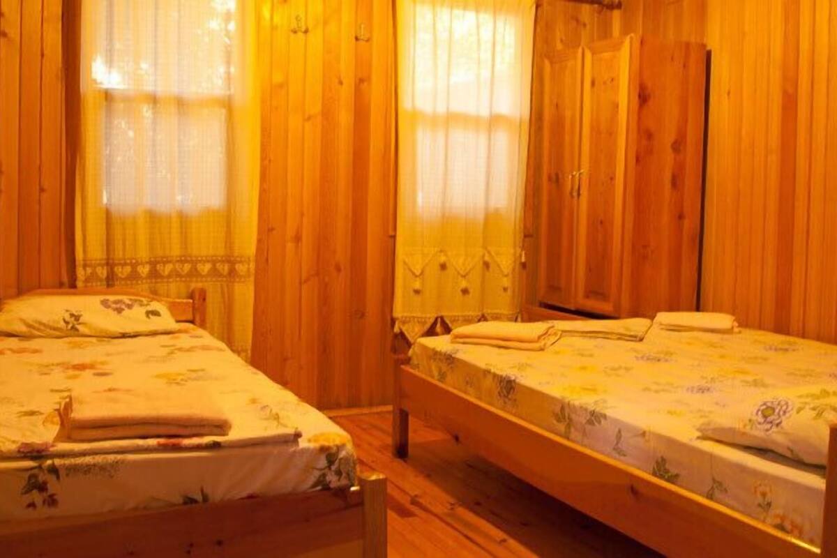 Una habitación con dos camas de madera, un armario de madera y una ventana con cortinas.