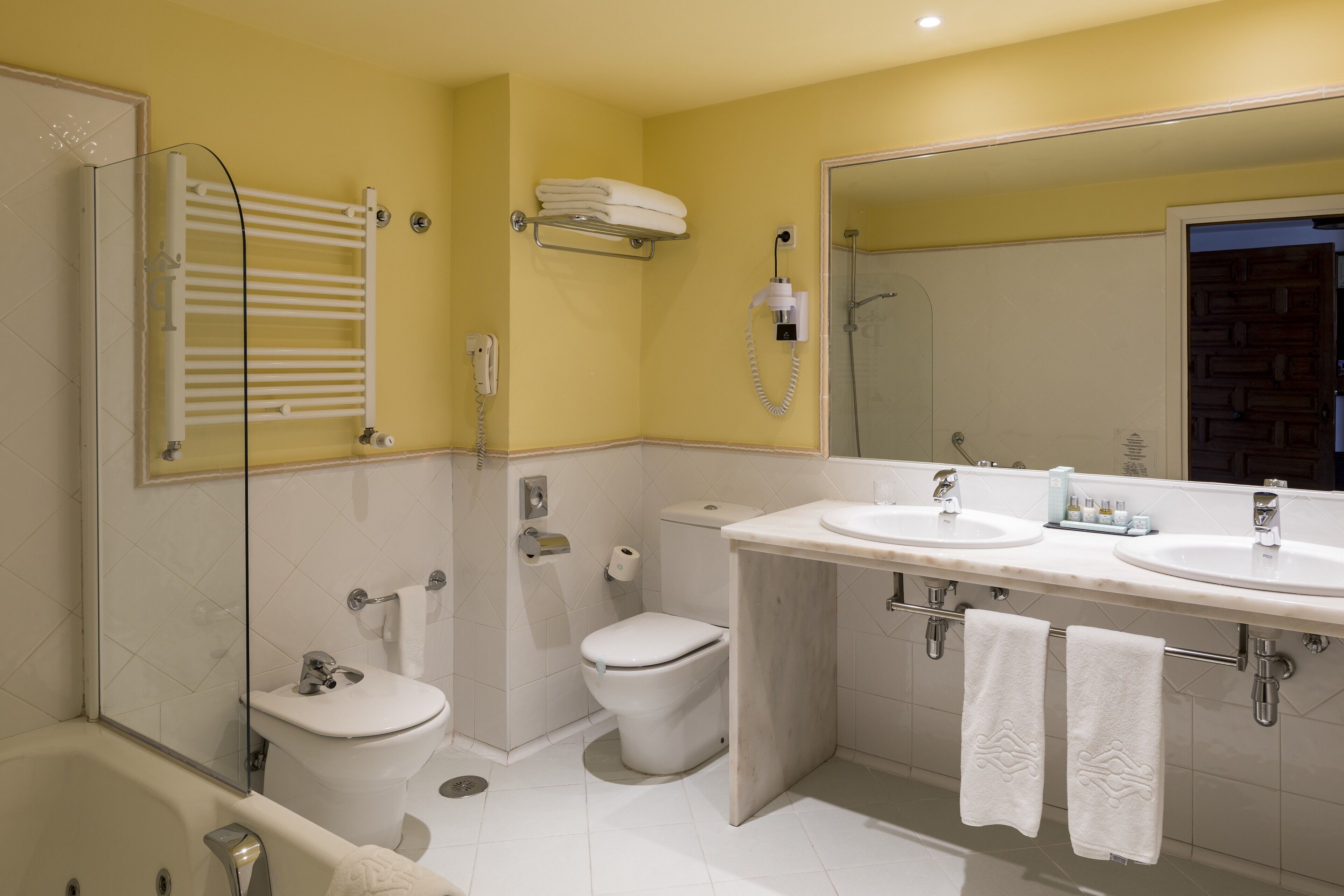 Un baño moderno con cabina de ducha de vidrio, inodoro blanco, bidé y tocador doble.