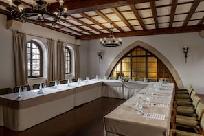 Ein Konferenzraum mit einem langen Tisch, mehreren Stühlen und einer Kronleuchter.