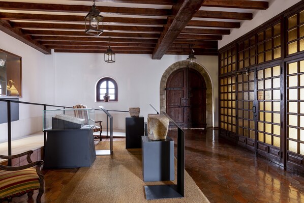 A spacious room with wooden beams, a stone fireplace, and a large window.