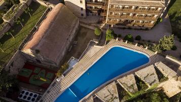 An aerial view of a hotel with a large swimming pool, a courtyard, and a building with multiple balconies.